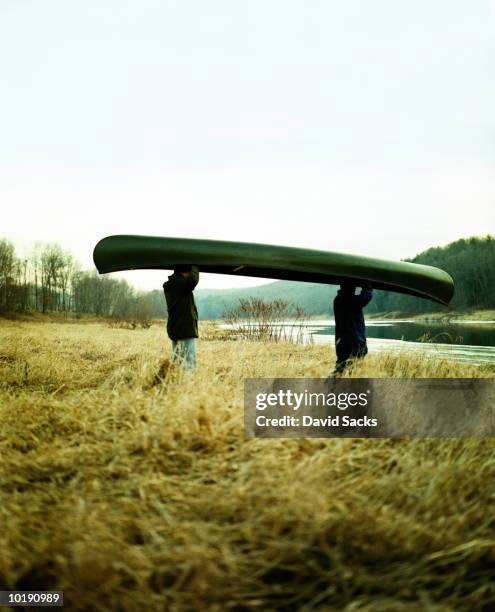 two men caryring canoe to lake - carrying canoe stock pictures, royalty-free photos & images