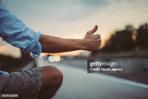 man holding hitchhiking thumb up - thumb stock pictures, royalty-free photos & images