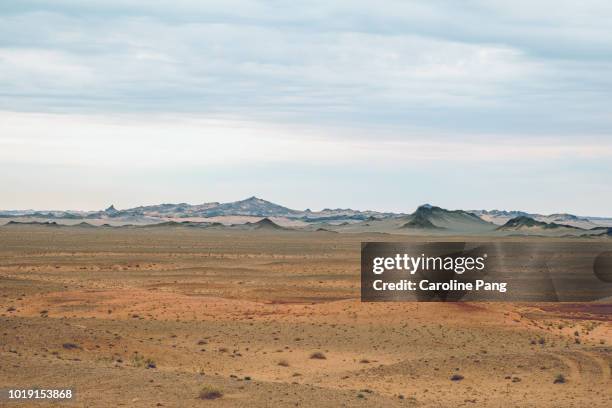 the varied landscape of the gobi desert includes jagged hills partially covered with sands which create fascinating layers of colours. - desolation wilderness stock pictures, royalty-free photos & images