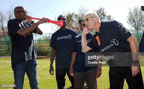Edwin Moses, Laureus academy chairman blows the Vuvuzela as Franz Beckenbauer, Laureus academy member listens during a visit by children from the...