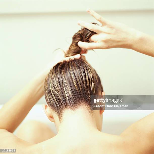 woman twisting hair, rear view - se laver les cheveux photos et images de collection