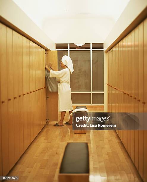 woman in bathrobe getting dressed in locker room - accappatoio foto e immagini stock
