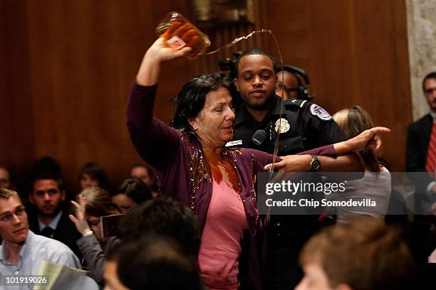 Commercial fisher-woman Diane Wilson of Seadrift, Texas, pours a jar of syrup made to look like oil over herself as a U.S. Capitol Police officer...