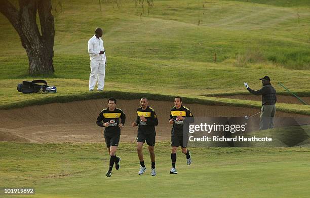 Goalkeepers Doni, Heurelho Gomes and Julio Cesar run past a golfer as he plays out of a bunker during the Brazil training session at Randpark Golf...