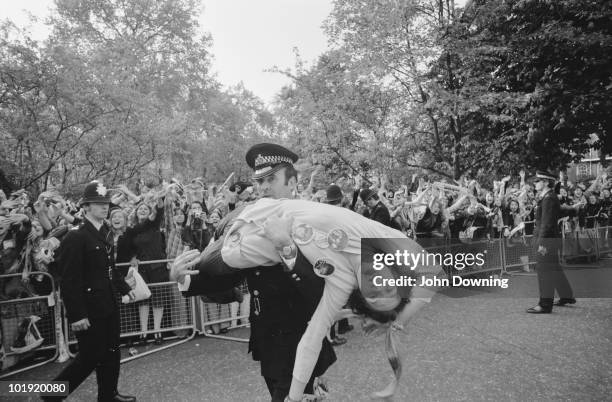 Policeman carries away a fan, injured in the crush, after members of The Osmonds pop group appeared on the balcony of a hotel in Belgravia, London...