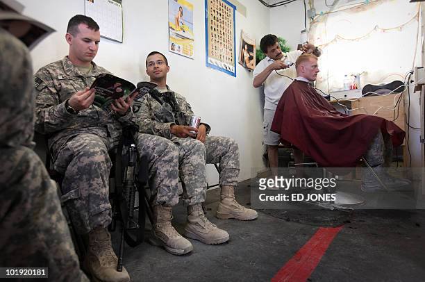 Barber shaves a US soldier's head as other soldiers wait in line at Camp Nathan Smith in Kandahar city on June 9, 2010. NATO, US and Afghan soldiers...