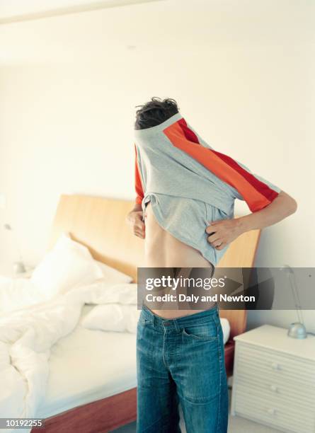 young man in bedroom getting dressed - getting dressed stock pictures, royalty-free photos & images