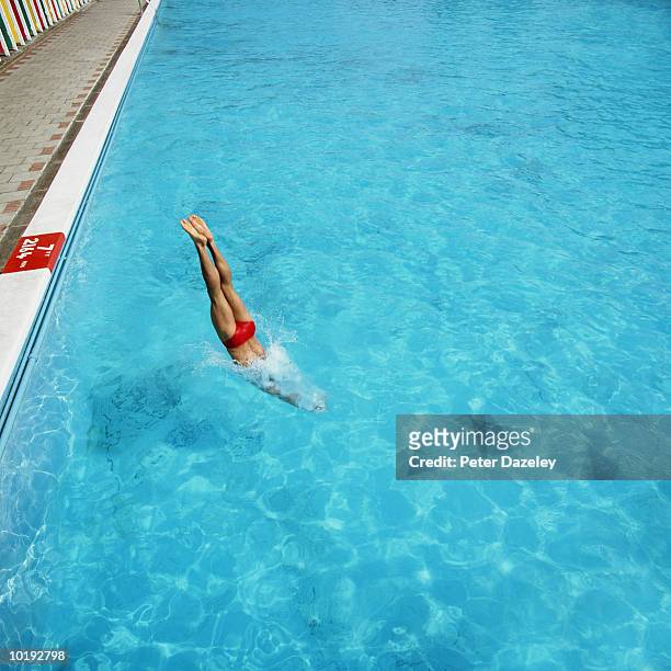 young man diving head first into swimming pool - zwembroek stockfoto's en -beelden