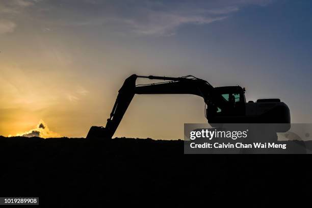 digger and excavator silhouette during sunset - grävmaskin bildbanksfoton och bilder