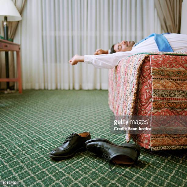 man relaxing on hotel room bed (focus on shoes) - jet lag 個照片及圖片檔