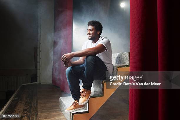 young man sitting on stage. - schauspieler stock-fotos und bilder