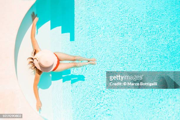 beautiful woman relaxing on pool steps. high angle view. - woman pool relax stockfoto's en -beelden