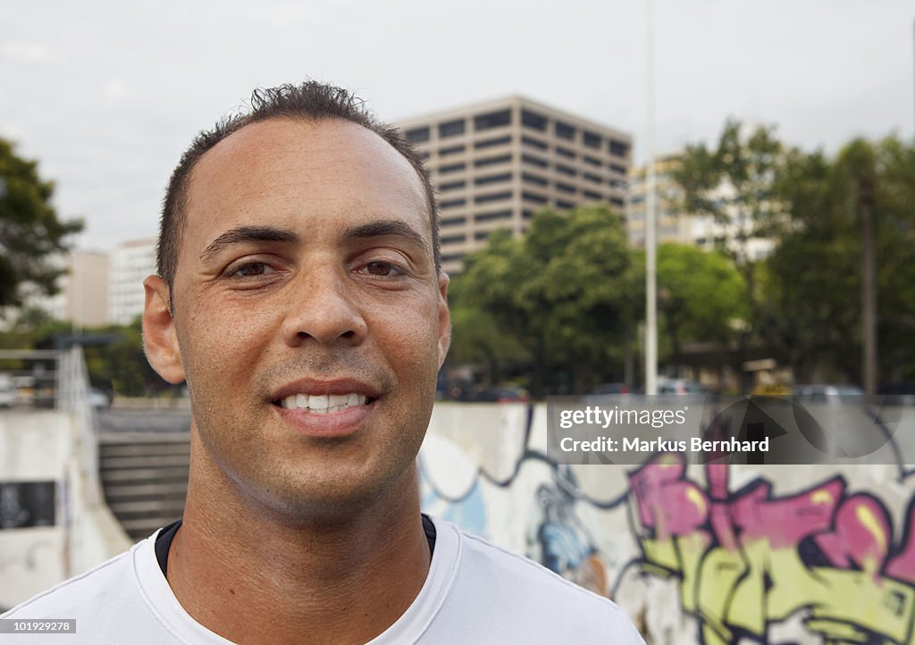 Confident man smiling in font of urban scenery.