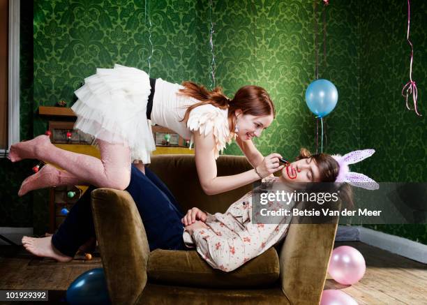 young woman painting face on sleeping boyfriend.  - woman after party stockfoto's en -beelden