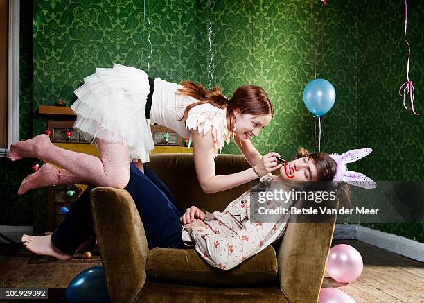 young woman painting face on sleeping boyfriend.  - messing about stock pictures, royalty-free photos & images