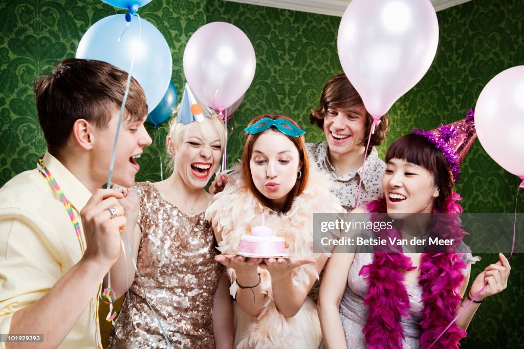 Young woman blowing out candle on birthday cake.