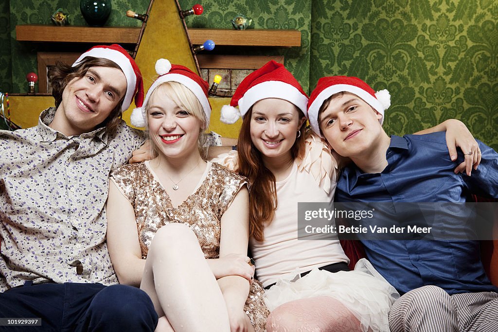 Four friends on sofa,wearing Christmas hats