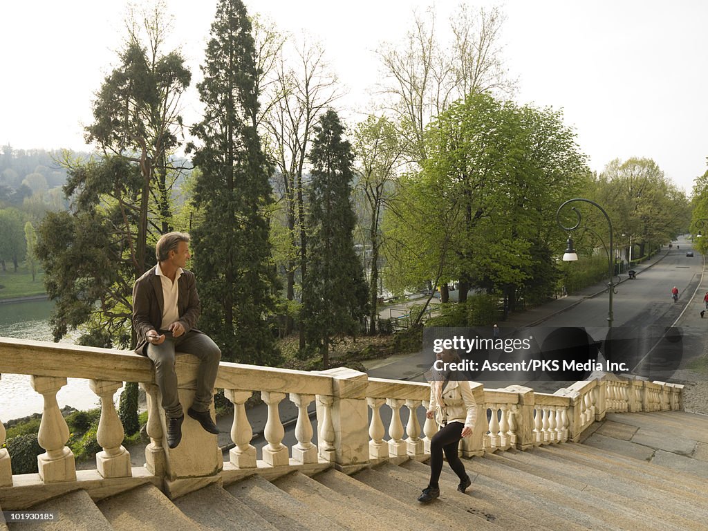 Woman walks up marble steps to meet man on railing