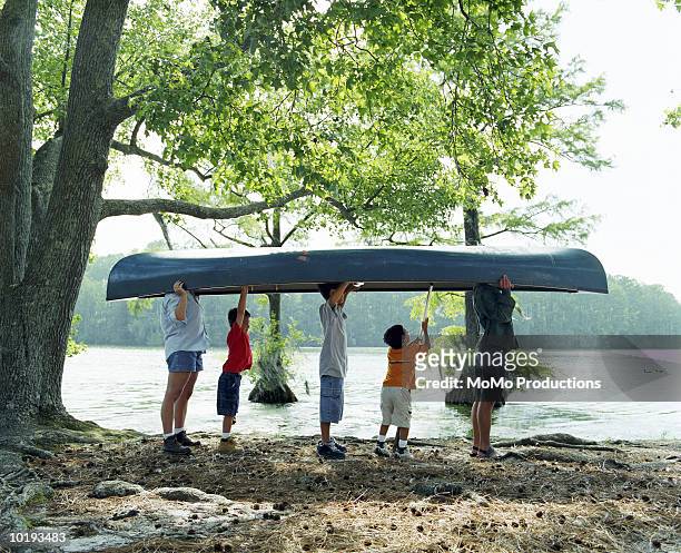 parents and sons (6-11) carrying canoe in park - carrying canoe stock pictures, royalty-free photos & images