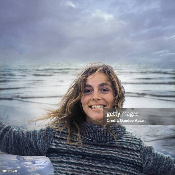 young woman on windy beach, portrait, close-up - tossing hair facing camera woman outdoors stock pictures, royalty-free photos & images