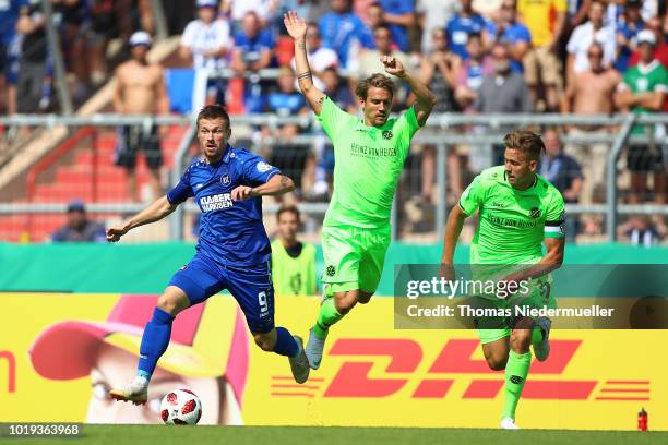 Marvin Pourie of Karlsruhe fights for the ball with Oliver Sorg and Waldemar Anton of Hannover during the DFB Cup first round match between...