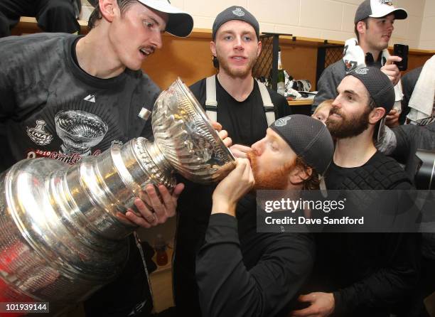 Tomas Kopecky of the Chicago Blackhawks pours champagne into the mouth of Brian Campbell from the Stanley Cup as Patrick Kane looks on after the...