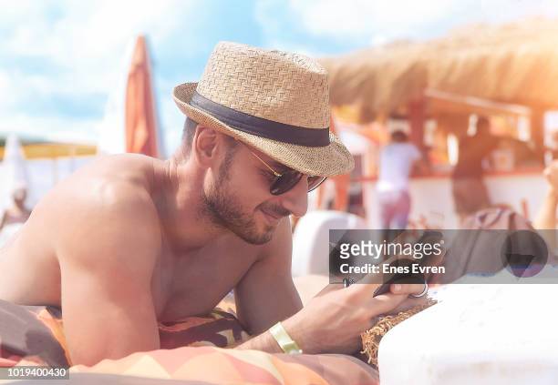man using mobile phone on the beach - beach club stock pictures, royalty-free photos & images