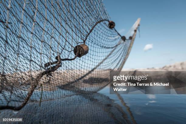 a fishing net on the beach in the water. - fishing net stock pictures, royalty-free photos & images
