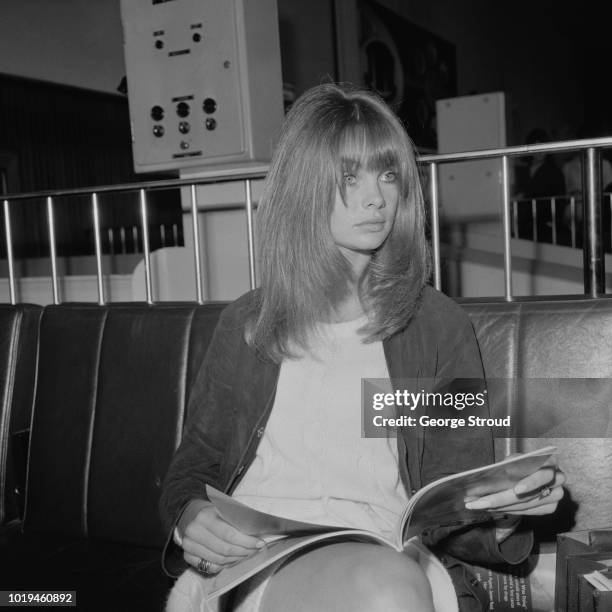 English model and actress Jean Shrimpton reading a magazine at Heathrow Airport, London, UK, 5th July 1965.