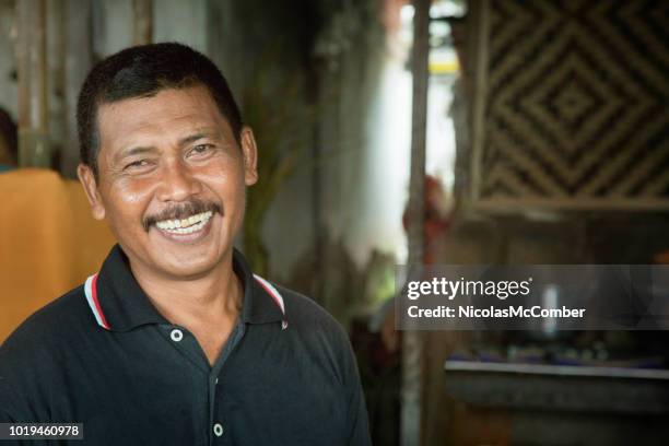 mature balinese man portrait smiling in small kitchen - indonesian ethnicity stock pictures, royalty-free photos & images