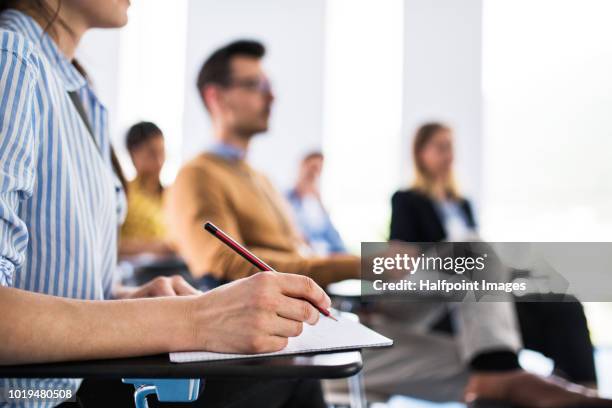 a close-up of an unrecognizable woman sitting in a board room,  making notes. - school close up stock-fotos und bilder