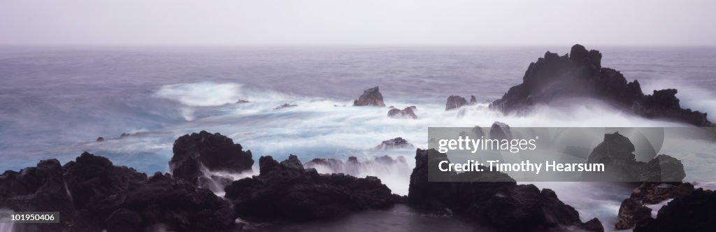 Ocean waves crashing against lava rock