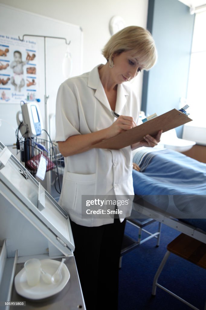 Nurse making notes on clipboard