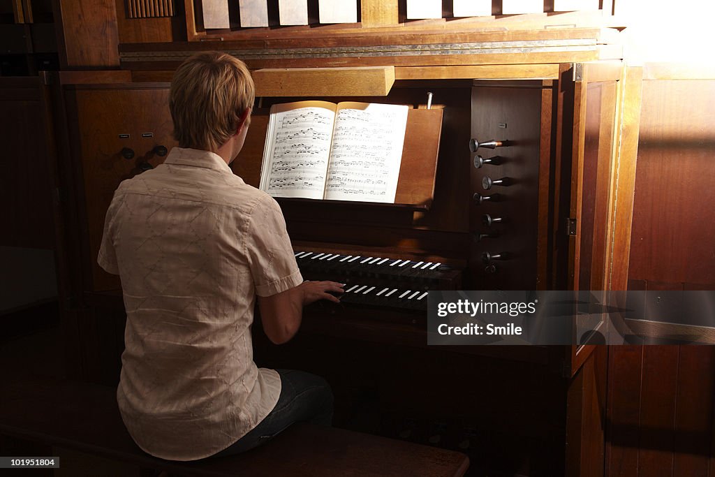 Organist playing the organ, rear view