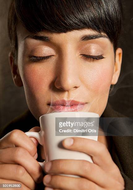 woman smelling steaming cup of coffee - 茶 熱飲 個照片及圖片檔