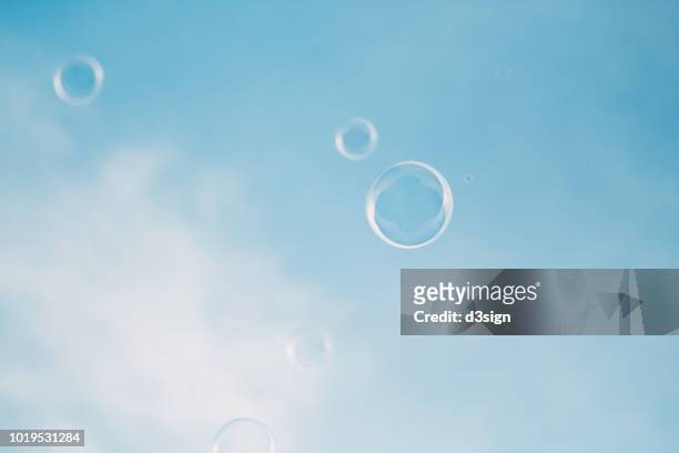 bubbles floating in the air against clear blue sky - froth stock-fotos und bilder