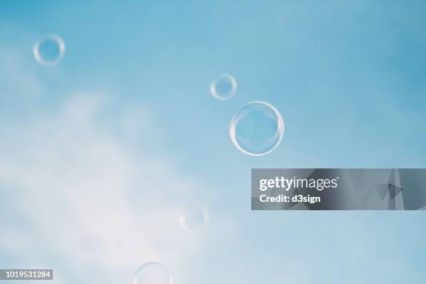 bubbles floating in the air against clear blue sky - pureté photos et images de collection