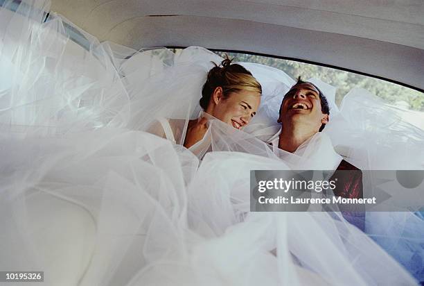 newly weds laughing in back of car - hochzeitskleid stock-fotos und bilder