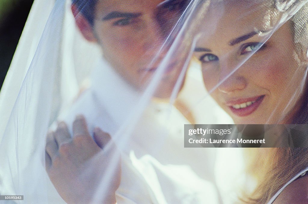 Newly weds under bride's veil, portrait, close-up