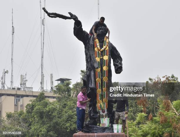 Congress workers decorate Rajiv Gandhi's statue on the eve of his 74th birth anniversary near Parliament street on August 19, 2018 in New Delhi,...