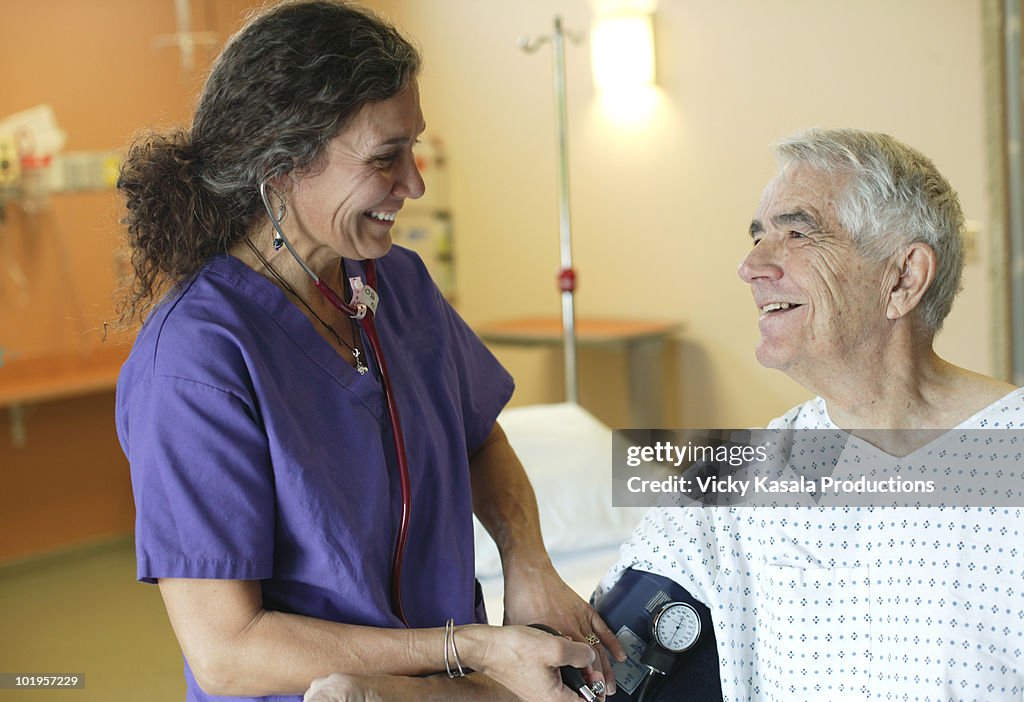 Nurse taking blood pressure of mature man 