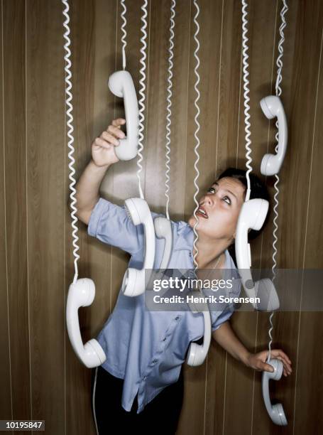 woman reaching for suspended telephone receivers - irrational fear stock pictures, royalty-free photos & images