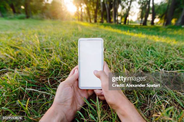 young man using smartphone while lying in the park on green grass, personal perspective view - finger dialing touch tone telephone stock pictures, royalty-free photos & images