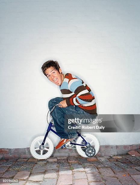 man riding child's bicycle with stabilisers, mouth open, portrait - happiness scale stock pictures, royalty-free photos & images