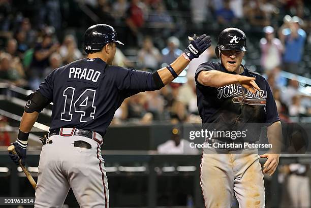 Brooks Conrad of the Atlanta Braves celebrates with teammate Martin Prado after scoring a run against the Arizona Diamondbacks during the ninth...