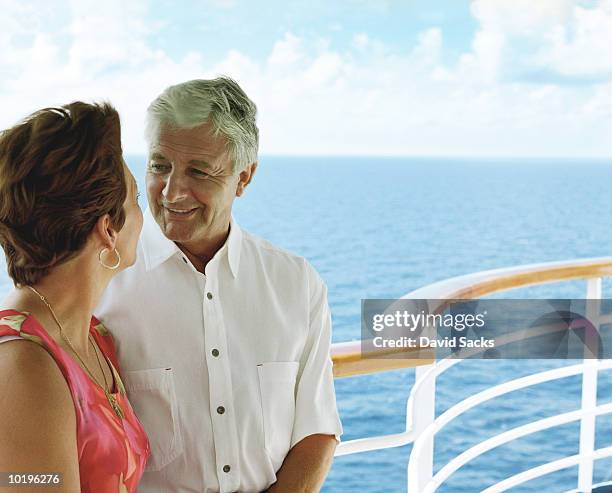 mature couple leaning against railing on cruise ship - imbarcazione per passeggeri foto e immagini stock