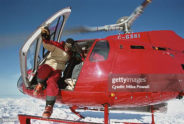 heli-skier exiting helicopter onto snowy mountain top - heli skiing stock pictures, royalty-free photos & images