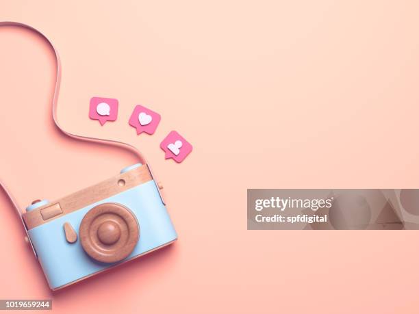 Vintage wooden photo camera with Pin heart, friends, comment, post. Overhead view of Traveler's accessories, Flat lay photography of Travel concept. Pink isolated background. 3d render