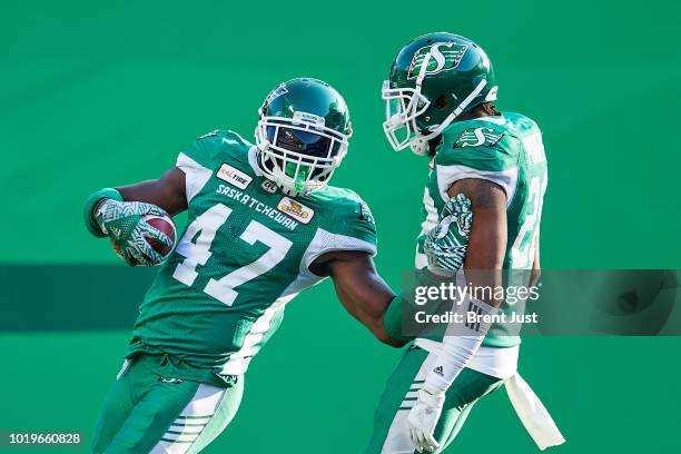 Samuel Eguavoen and Loucheiz Purifoy of the Saskatchewan Roughriders celebrate a touchdown on a return of a blocked punt in the first half of the...