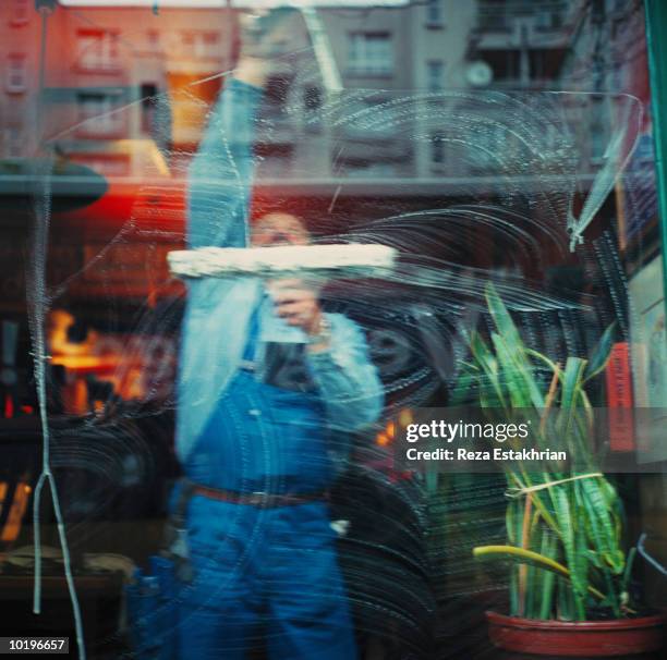 man cleaning store window with squeegee - window cleaning stock pictures, royalty-free photos & images